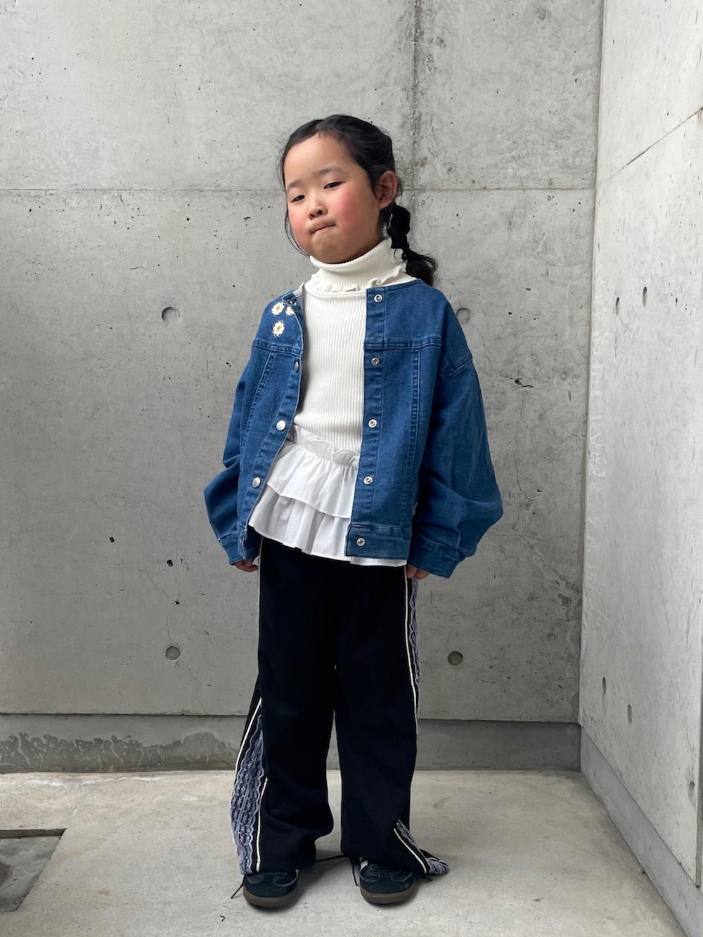 ブラック系のパンツ、ブルー系のデニムジャケット、ホワイト系のニット/セーターを着用したキッズの春コーディネートの3枚目の写真