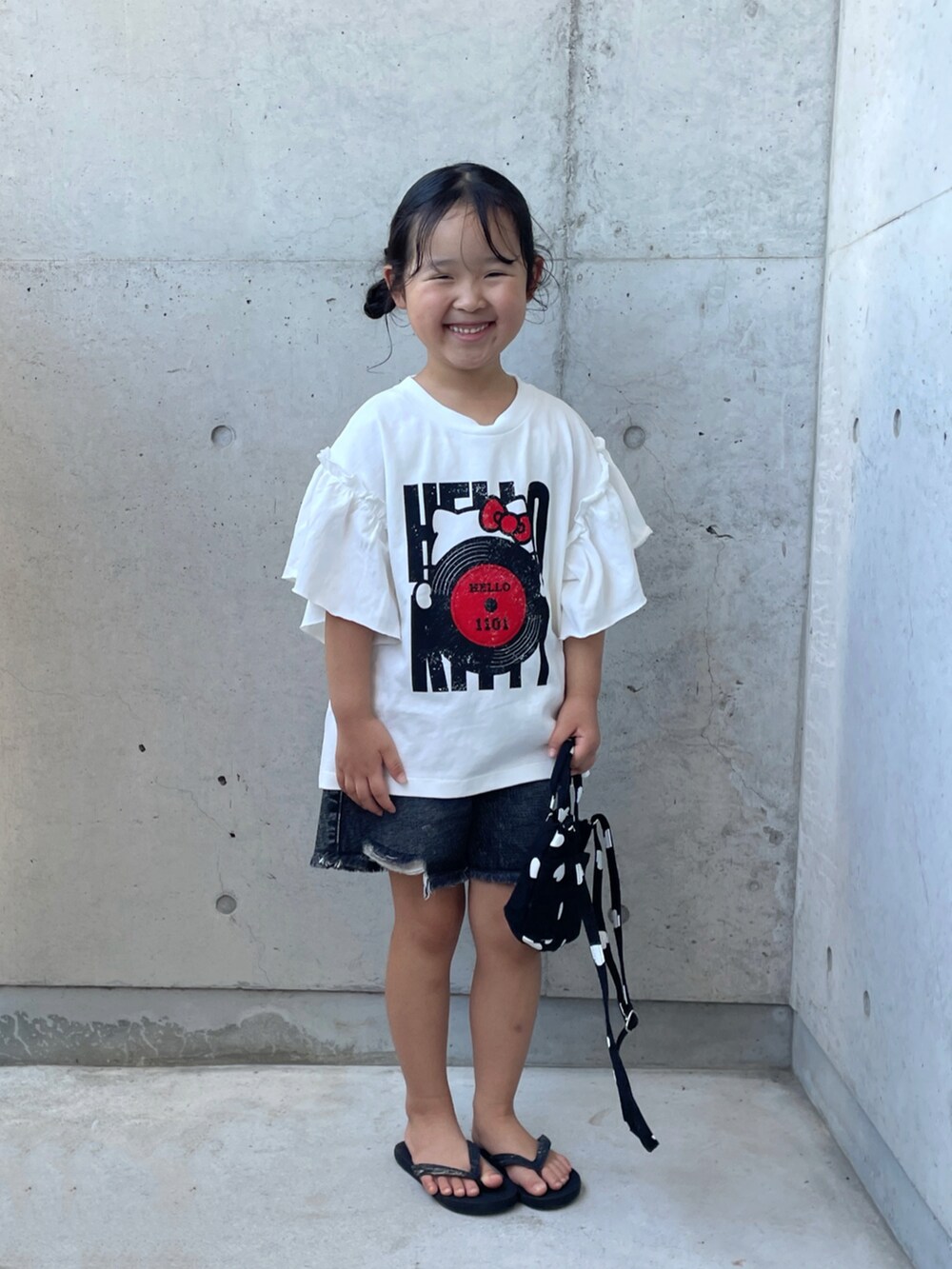 ブラック系のデニムパンツ、ブラック系のサンダル、ブラック系のショルダーバッグを着用したキッズの夏コーディネートの3枚目の写真