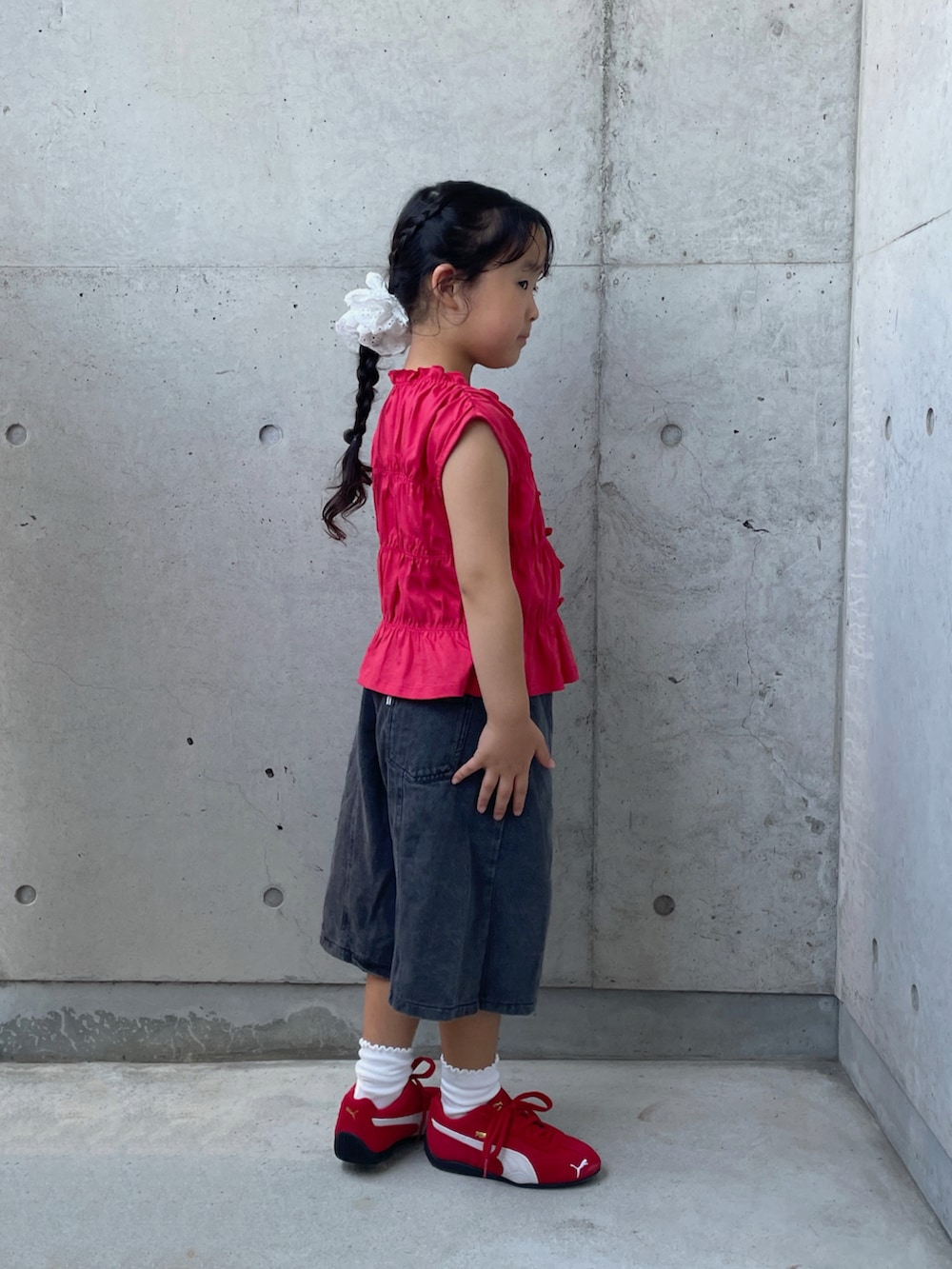 ブラック系のデニムパンツ、レッド系のスニーカー、レッド系のトップスを着用したキッズの夏コーディネートの2枚目の写真