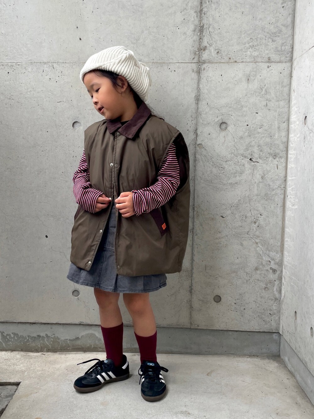 レッド系のTシャツ/カットソー、グリーン系のブルゾン、グレー系のスカートを着用したキッズの秋コーディネートの4枚目の写真