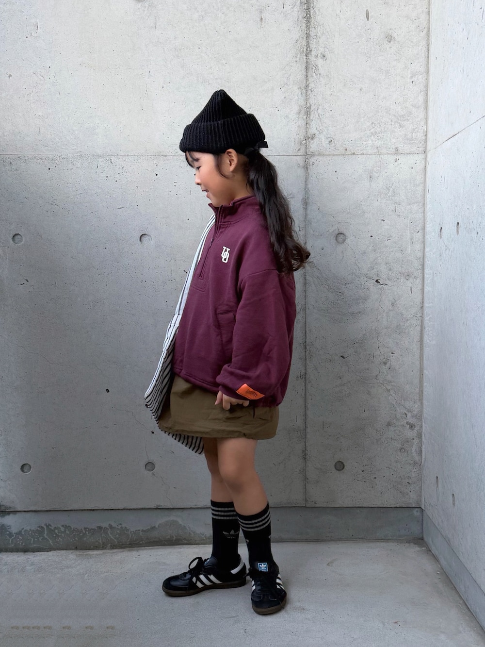 ブラック系のスニーカー、グリーン系のスカート、レッド系のスウェットを着用したキッズの秋コーディネートの2枚目の写真