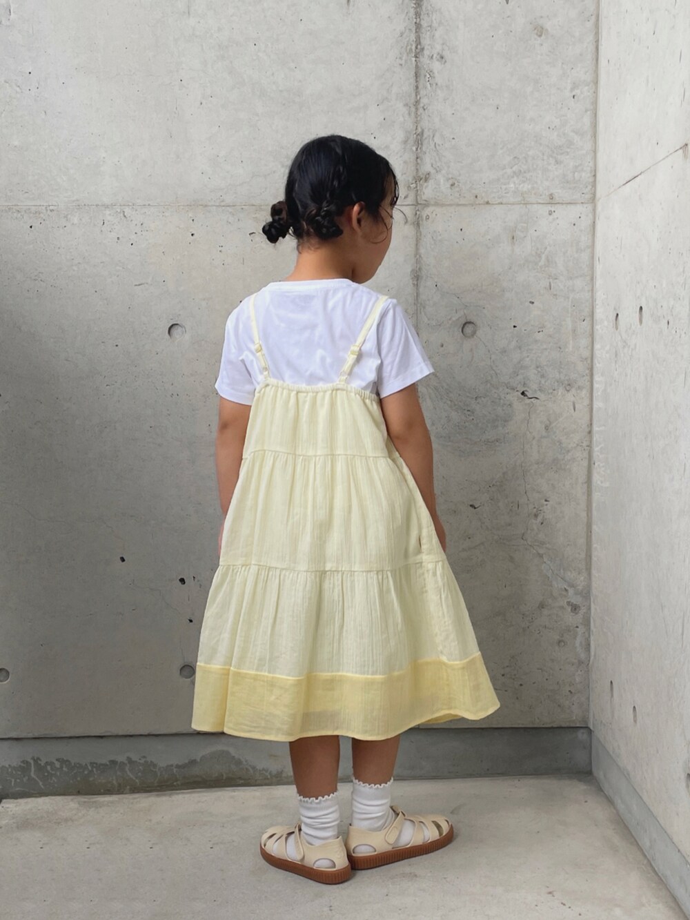 ホワイト系のサンダル、ホワイト系のTシャツ/カットソー、イエロー系のワンピースを着用したキッズの夏コーディネートの3枚目の写真