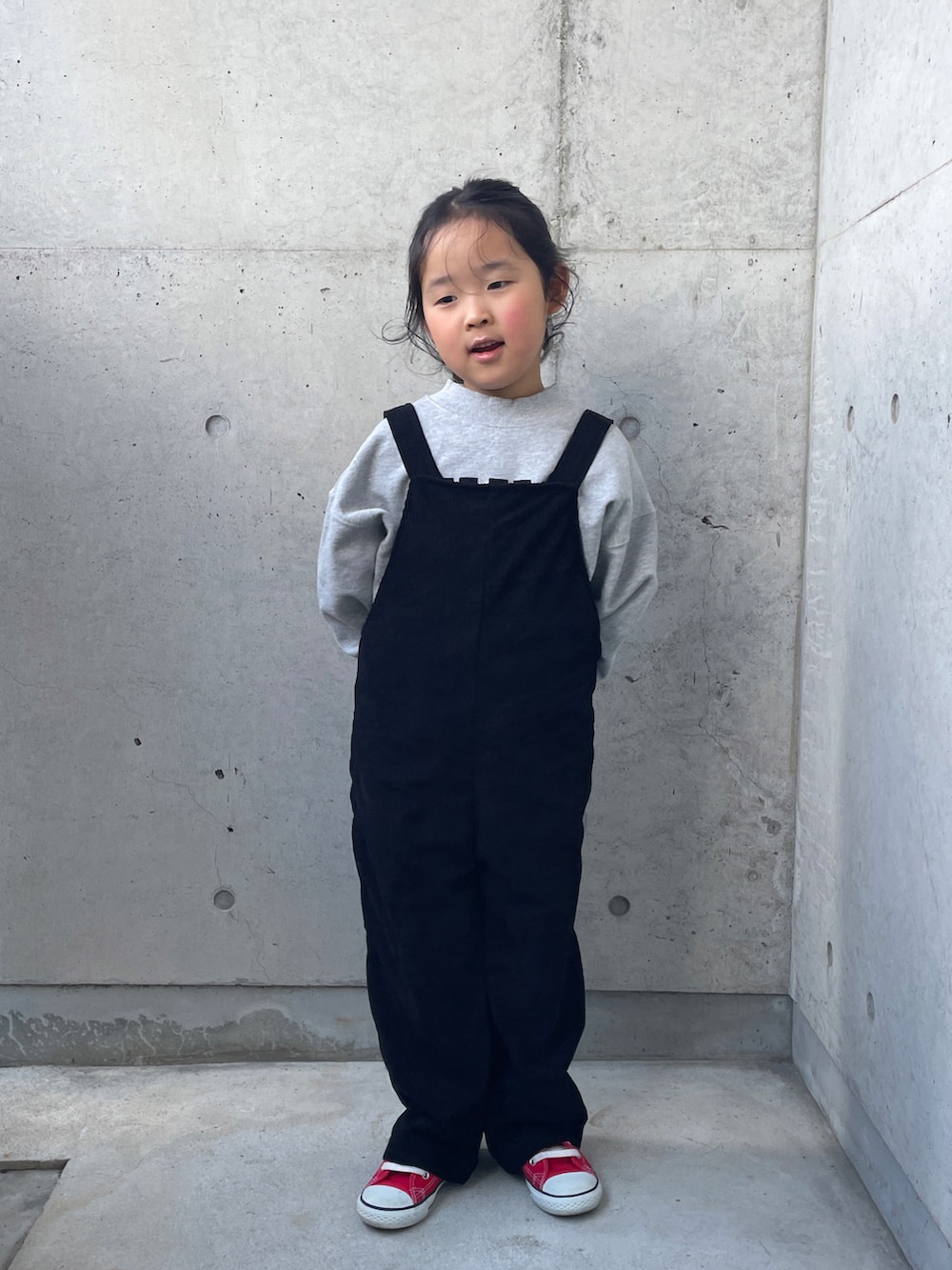 グレー系のスウェット、ブラック系のサロペット/オーバーオール、ピンク系のニット/セーターを着用したキッズの冬コーディネートの3枚目の写真