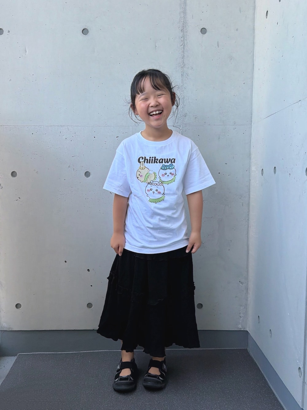ブラック系のサンダル、ブラック系のスカート、ホワイト系のTシャツ/カットソーを着用したキッズの夏コーディネートの3枚目の写真