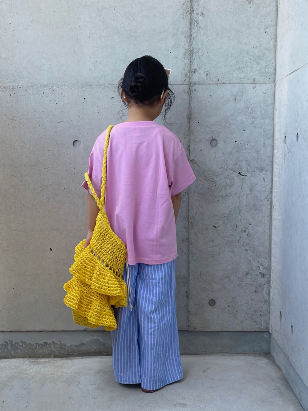 ピンク系のTシャツ/カットソー、ブルー系のパンツ、イエロー系のかごバッグを着用したキッズの夏コーディネートの3枚目の写真