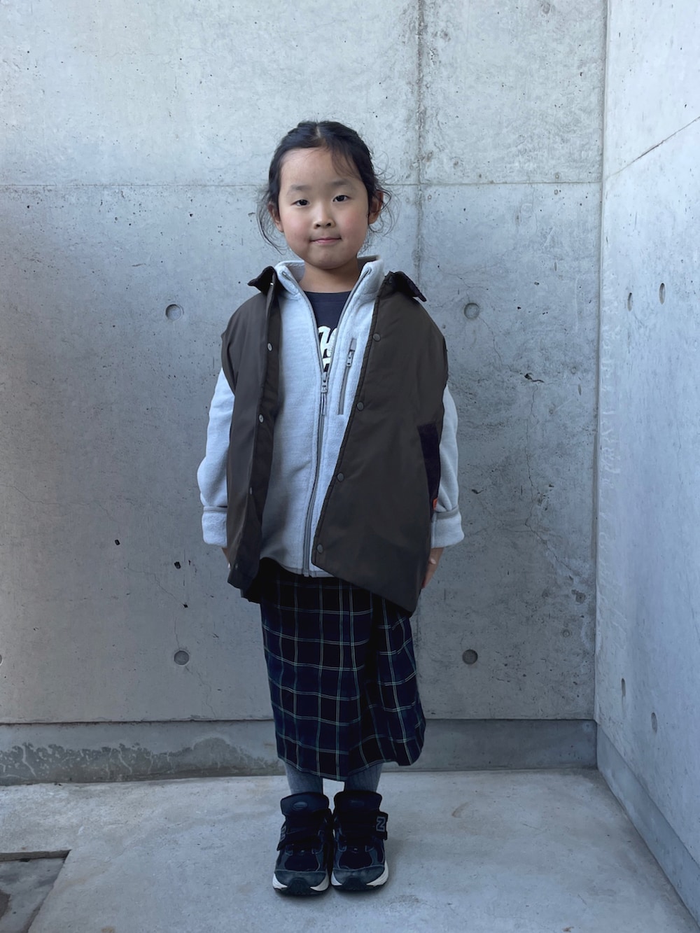 グレー系のトップス、グレー系のTシャツ/カットソー、ブラウン系のスカートを着用したキッズの冬コーディネートの3枚目の写真