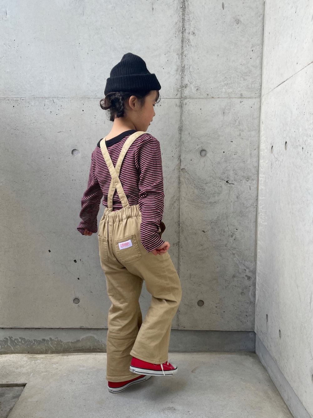 レッド系のスニーカー、レッド系のTシャツ/カットソー、ベージュ系のサロペット/オーバーオールを着用したキッズの春コーディネートの2枚目の写真