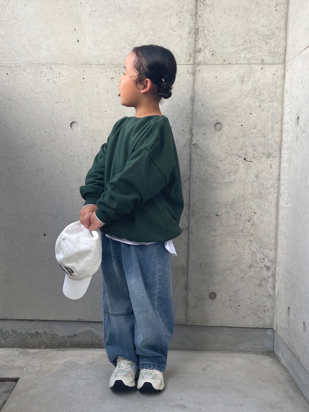 グリーン系のスウェット、ブルー系のデニムパンツ、ホワイト系のスニーカーを着用したキッズの秋コーディネートの4枚目の写真