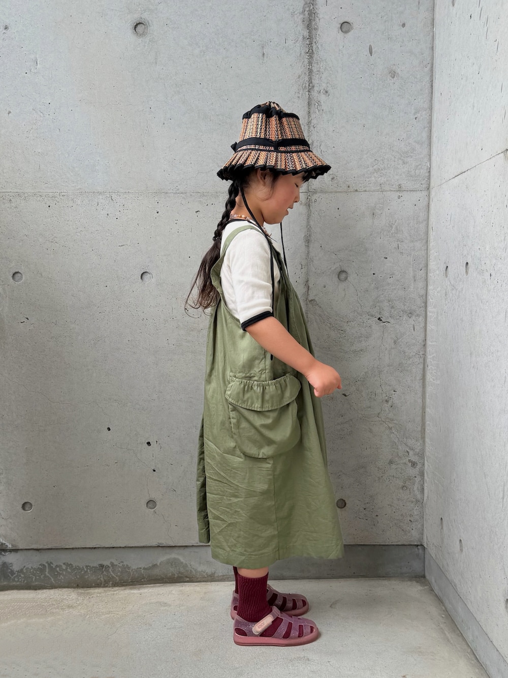 グリーン系のジャンパースカート、ホワイト系のTシャツ/カットソー、その他のサンダルを着用したキッズの春コーディネートの2枚目の写真