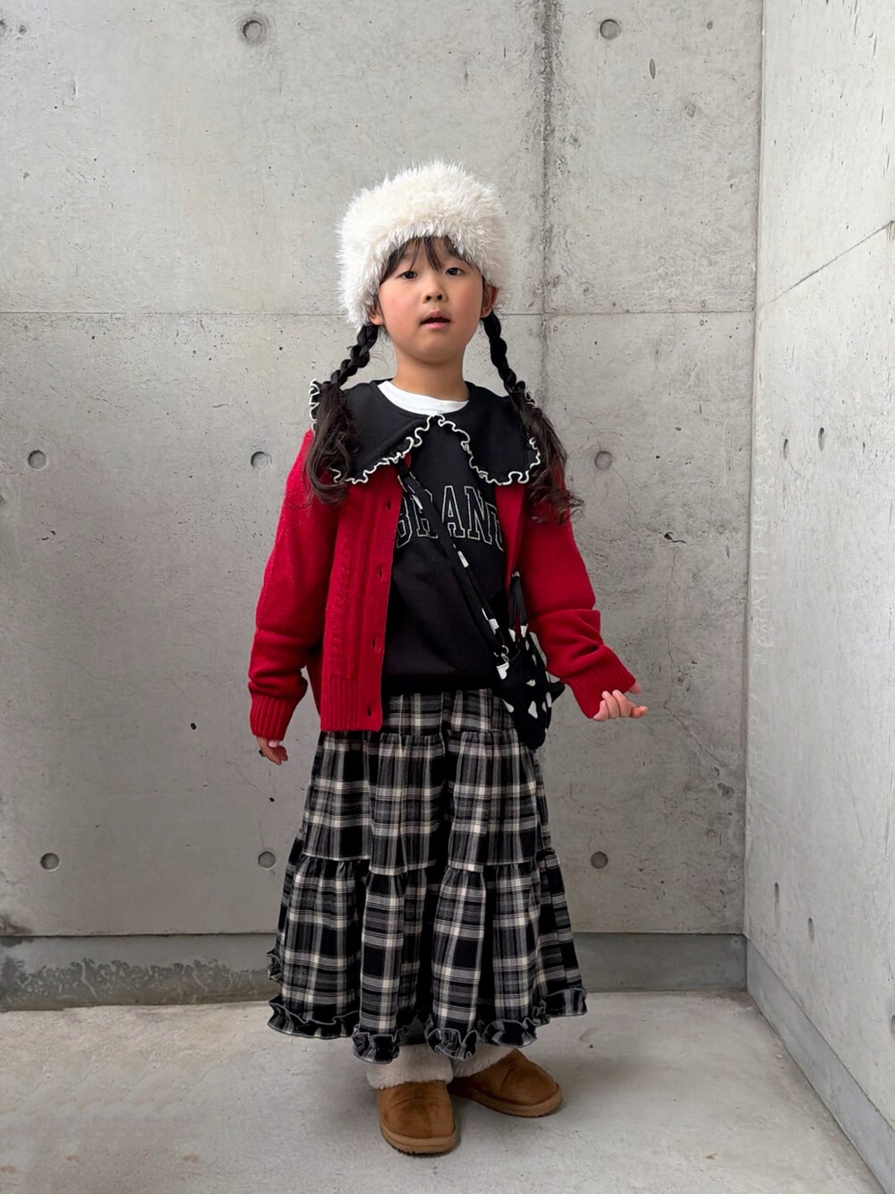 ブラック系のスウェット、ブラウン系のスカート、ブラック系のショルダーバッグを着用したキッズの冬コーディネートの5枚目の写真