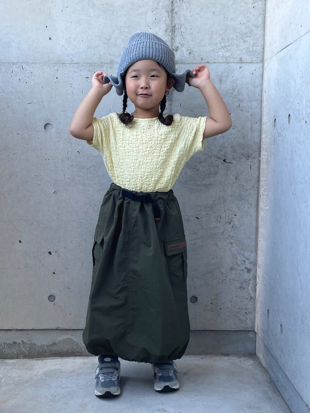ベージュ系のTシャツ/カットソー、グレー系のスニーカー、グリーン系のスカートを着用したキッズの秋コーディネートの3枚目の写真