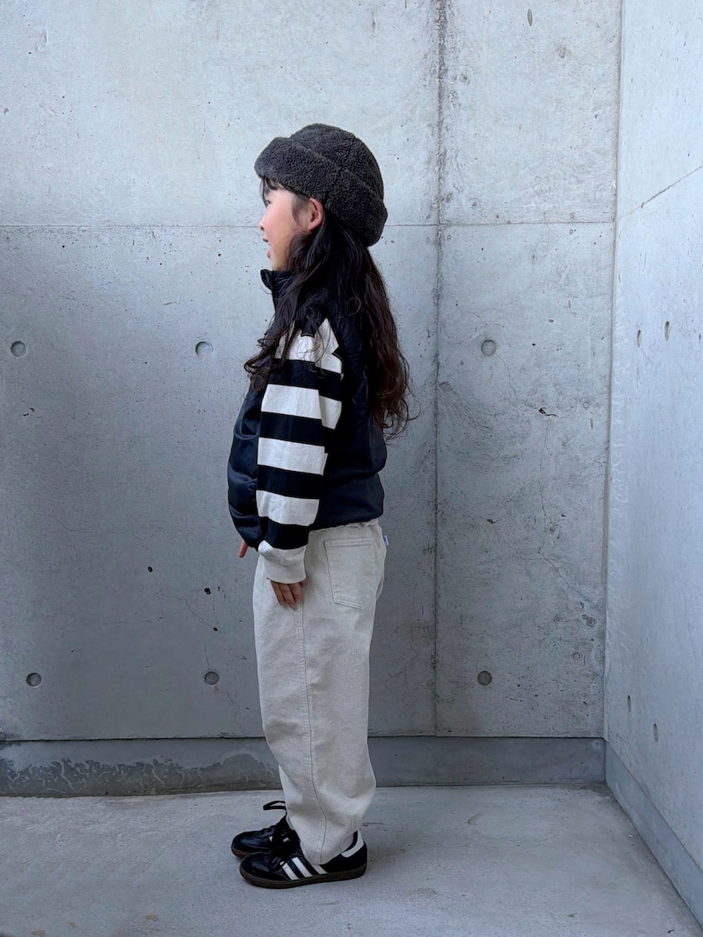 ベージュ系のその他パンツ、ブラック系のスニーカー、ブラック系のベストを着用したキッズの秋コーディネートの2枚目の写真