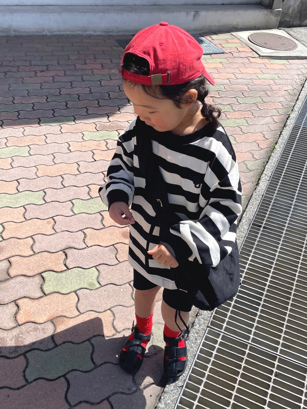 ブラック系のTシャツ/カットソー、ブラック系のショルダーバッグ、ブラック系のサンダルを着用したキッズの春コーディネートの4枚目の写真