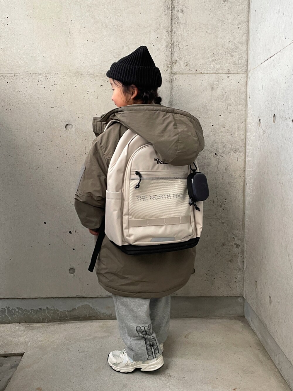 グリーン系のブルゾン、ホワイト系のバックパック/リュック、グレー系のパンツを着用したキッズの冬コーディネートの2枚目の写真