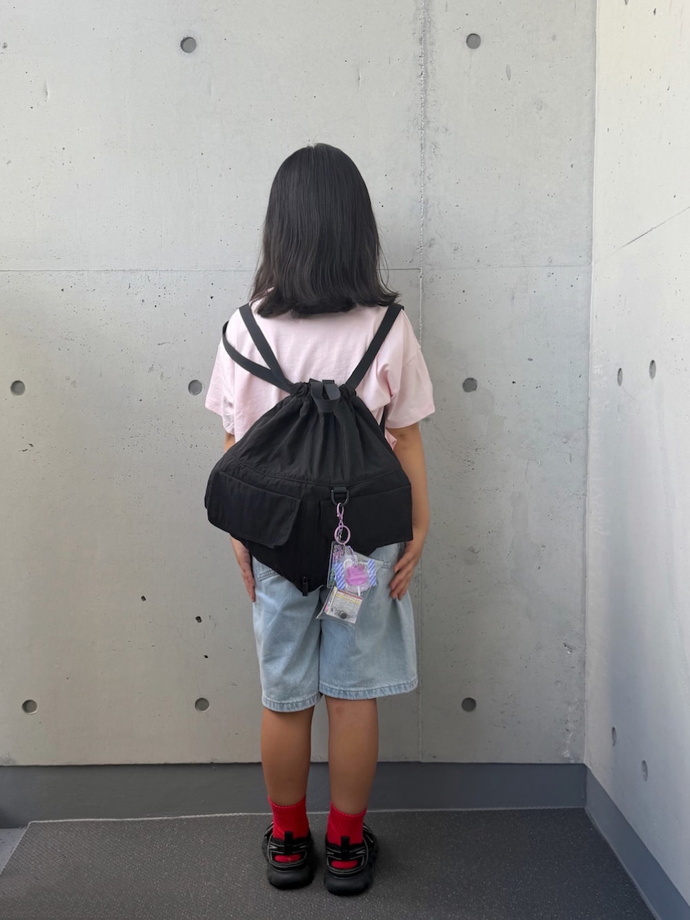 ブラック系のサンダル、ブラック系のバックパック/リュック、ピンク系のTシャツ/カットソーを着用したキッズの秋コーディネートの2枚目の写真