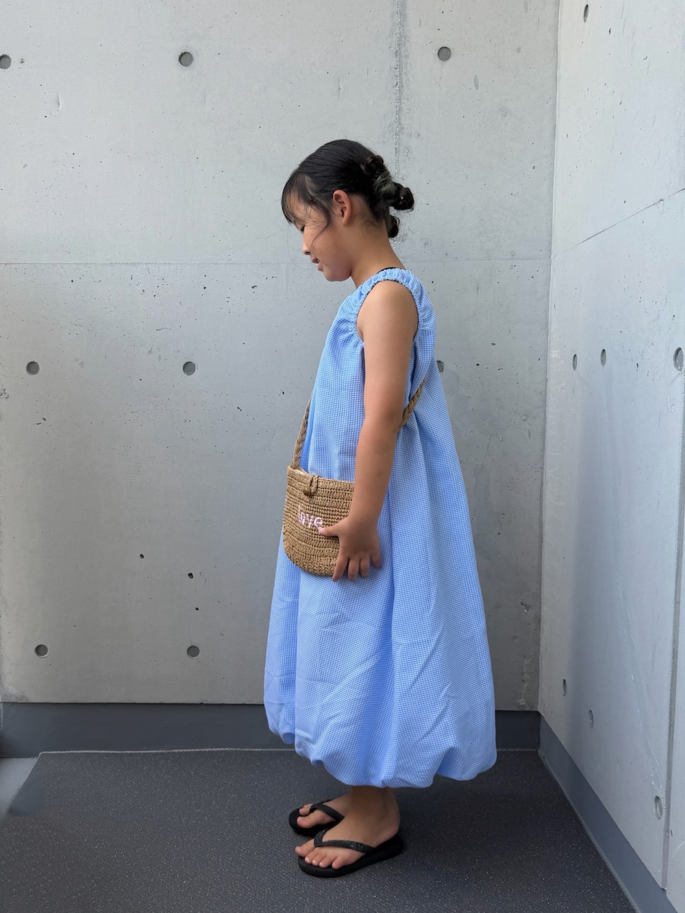 ブルー系のワンピース、ベージュ系のショルダーバッグ、ブラック系のサンダルを着用したキッズの夏コーディネートの2枚目の写真