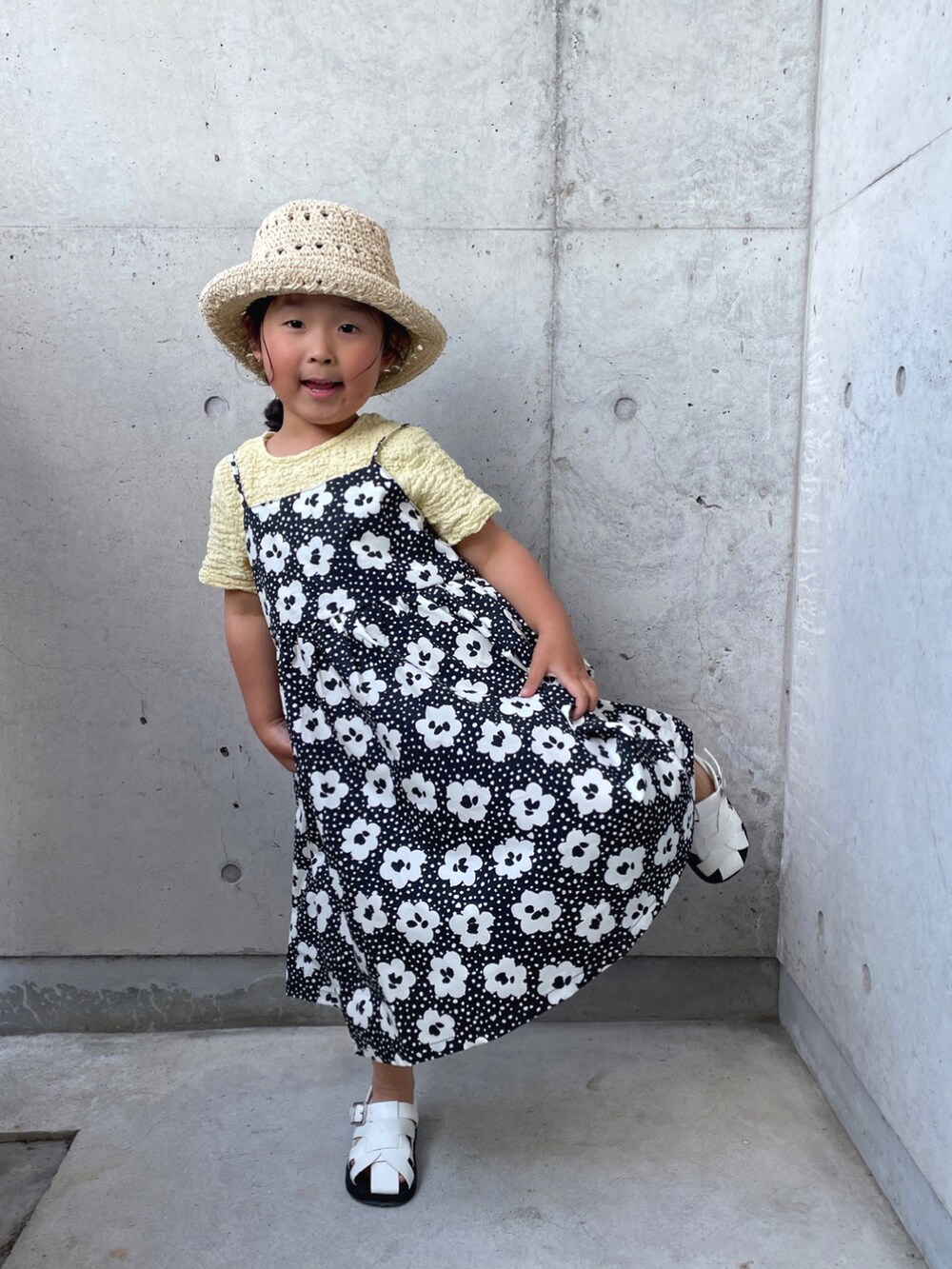 ブラック系のワンピース、ホワイト系のサンダル、ベージュ系のTシャツ/カットソーを着用したキッズの春コーディネートの3枚目の写真