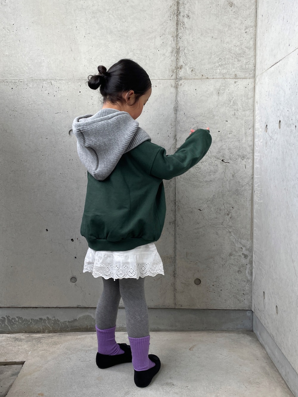 グリーン系のトップス、ホワイト系のパンツ、ブラック系のその他シューズを着用したキッズの冬コーディネートの3枚目の写真