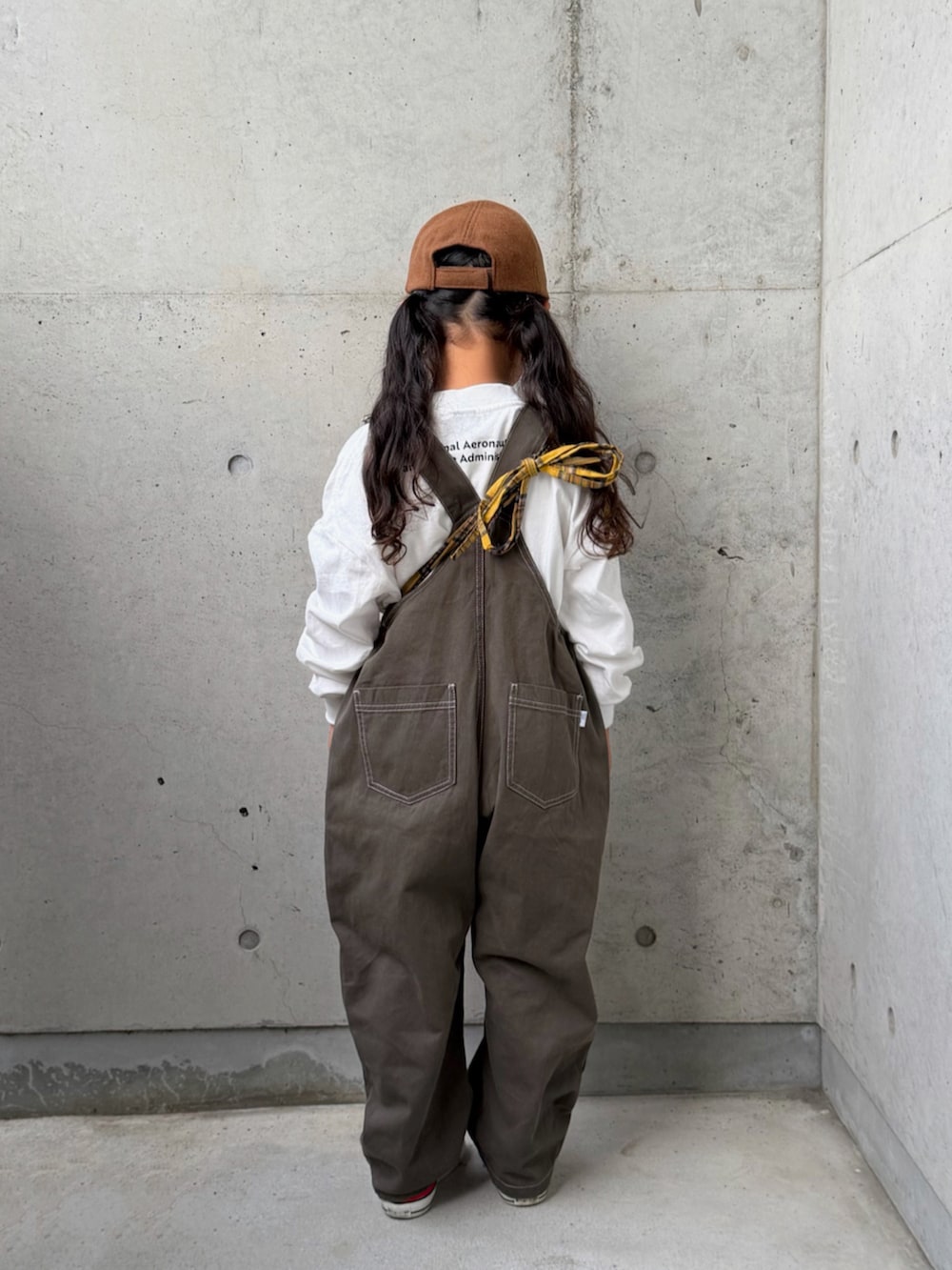 レッド系のスニーカー、グレー系のサロペット/オーバーオール、イエロー系のバックパック/リュックを着用したキッズの秋コーディネートの3枚目の写真