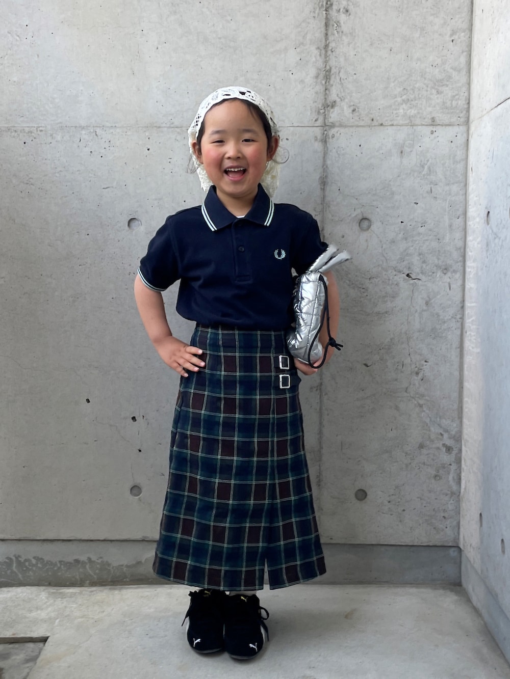 ブラウン系のスカート、ブルー系のポロシャツ、ブラック系のスニーカーを着用したキッズの春コーディネートの4枚目の写真