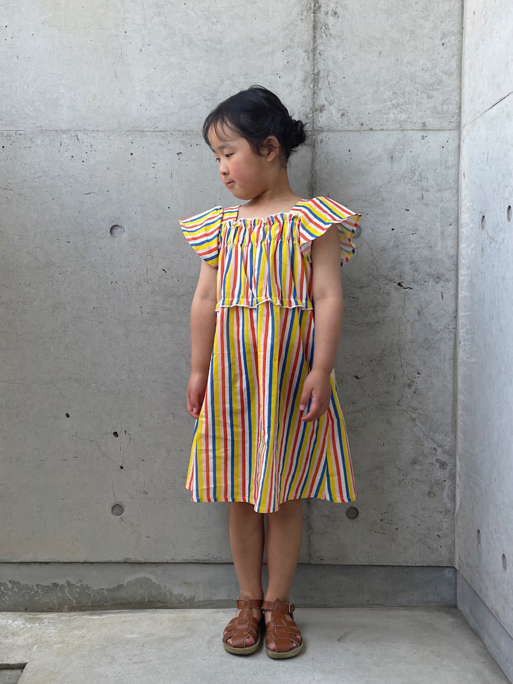 ベージュ系のサンダル、イエロー系のワンピースを着用したキッズの春コーディネートの4枚目の写真