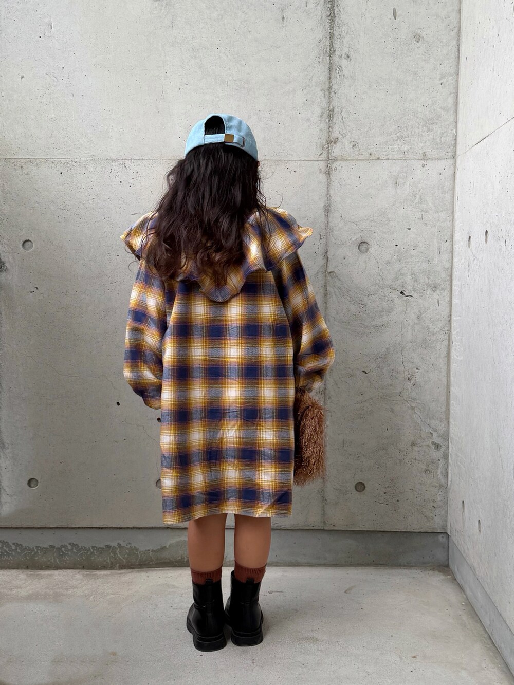 イエロー系のワンピース、ブラウン系のショルダーバッグ、ブラック系のブーツを着用したキッズの秋コーディネートの3枚目の写真