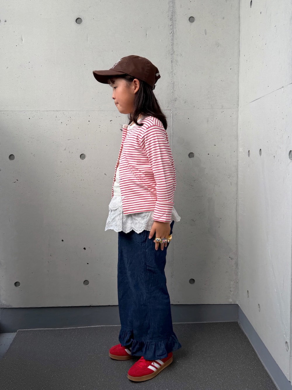 ブルー系のデニムパンツ、レッド系のスニーカー、レッド系のカーディガン/ボレロを着用したキッズの秋コーディネートの2枚目の写真