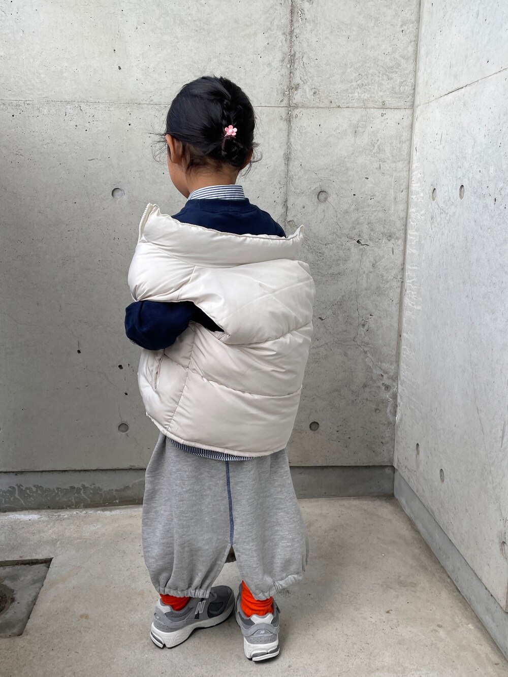 ホワイト系のダウンベスト、ブルー系のスウェット、グレー系のスカートを着用したキッズの春コーディネートの2枚目の写真