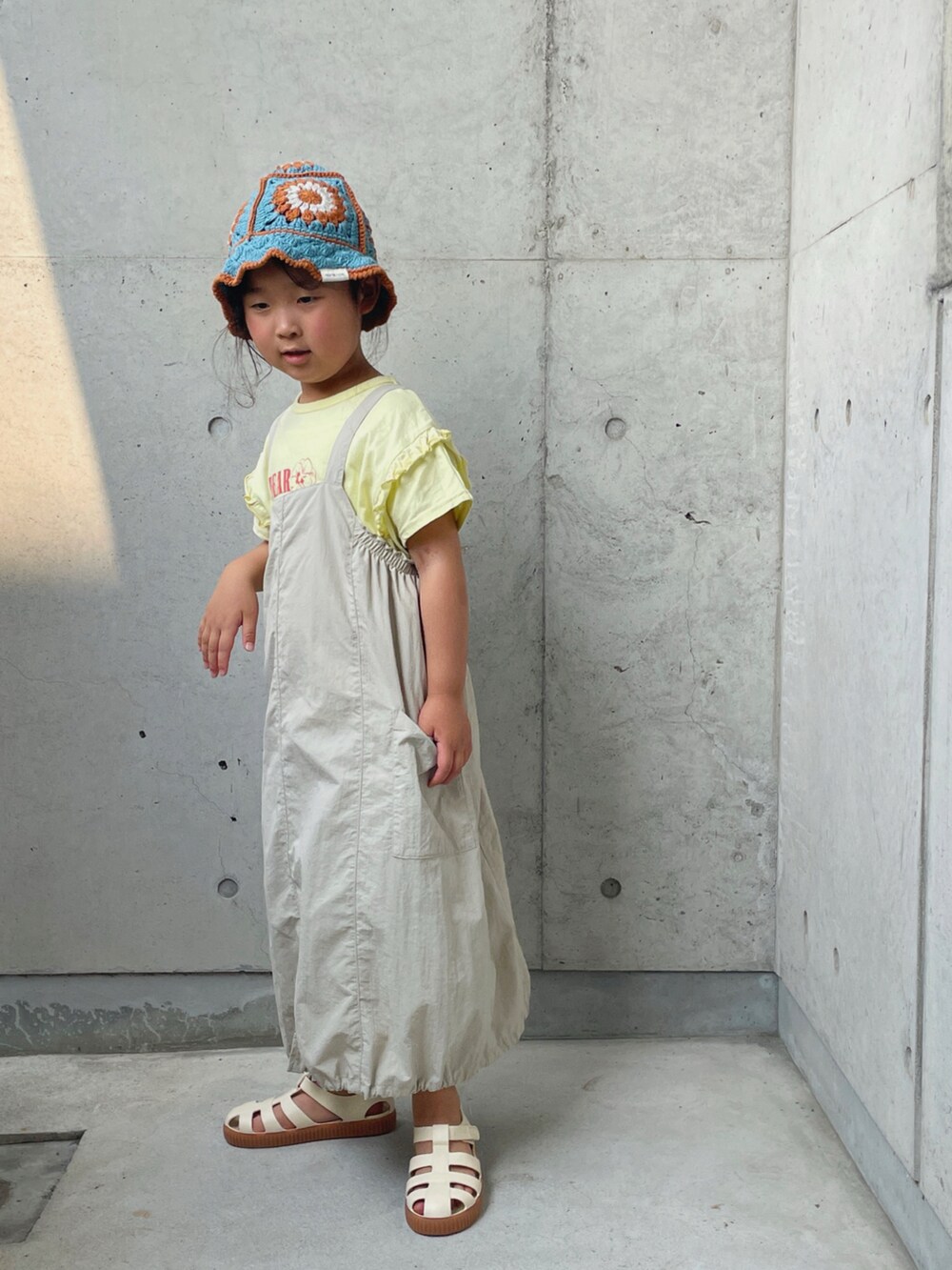 ベージュ系のTシャツ/カットソー、ベージュ系のワンピース、ホワイト系のサンダルを着用したキッズの夏コーディネートの3枚目の写真