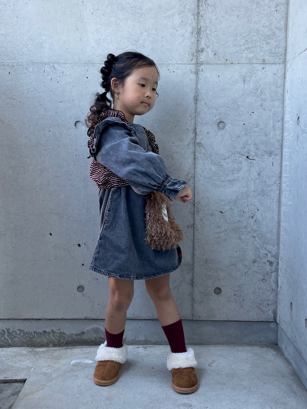 ブラウン系のショルダーバッグ、レッド系のキャミソール、ブラウン系のブーツを着用したキッズの秋コーディネートの4枚目の写真