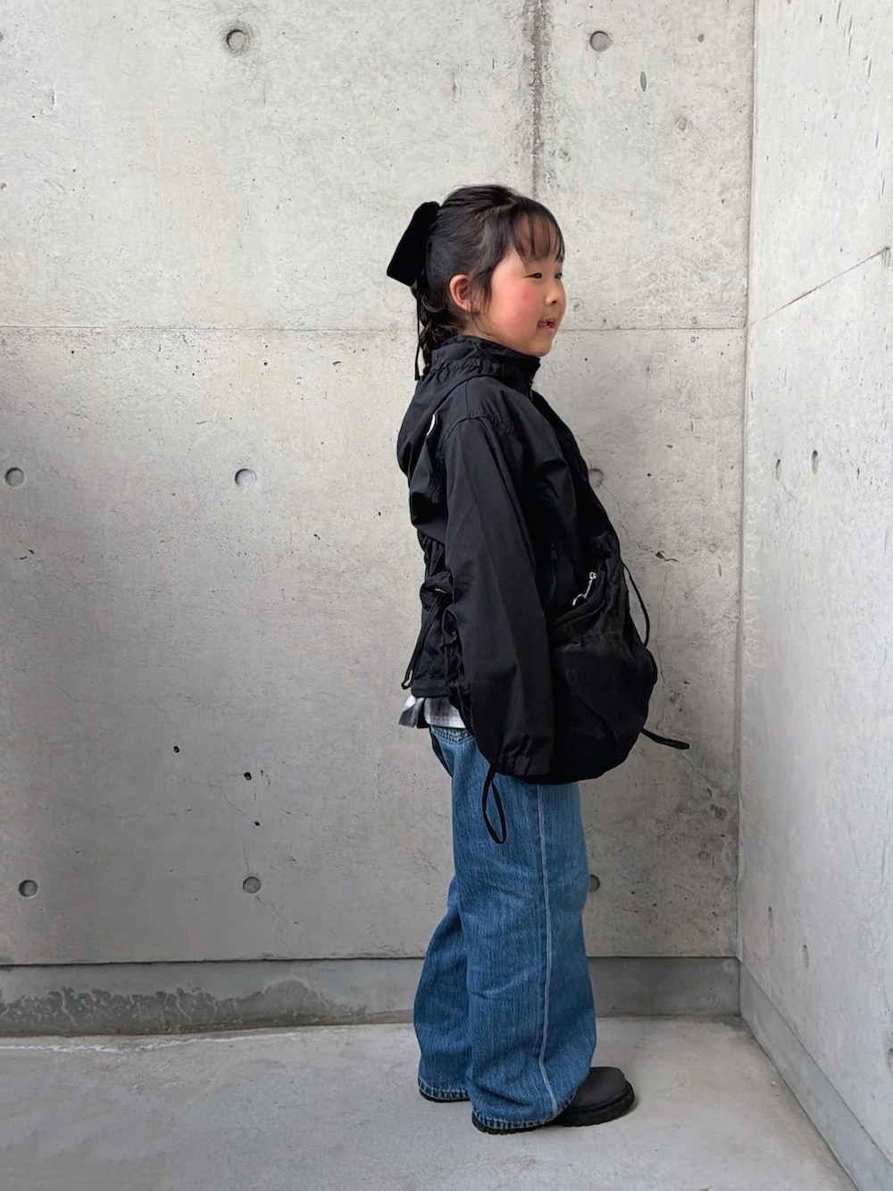 ブラック系のスカート、グレー系のブーツ、ブラック系のマウンテンパーカーを着用したキッズの春コーディネートの5枚目の写真