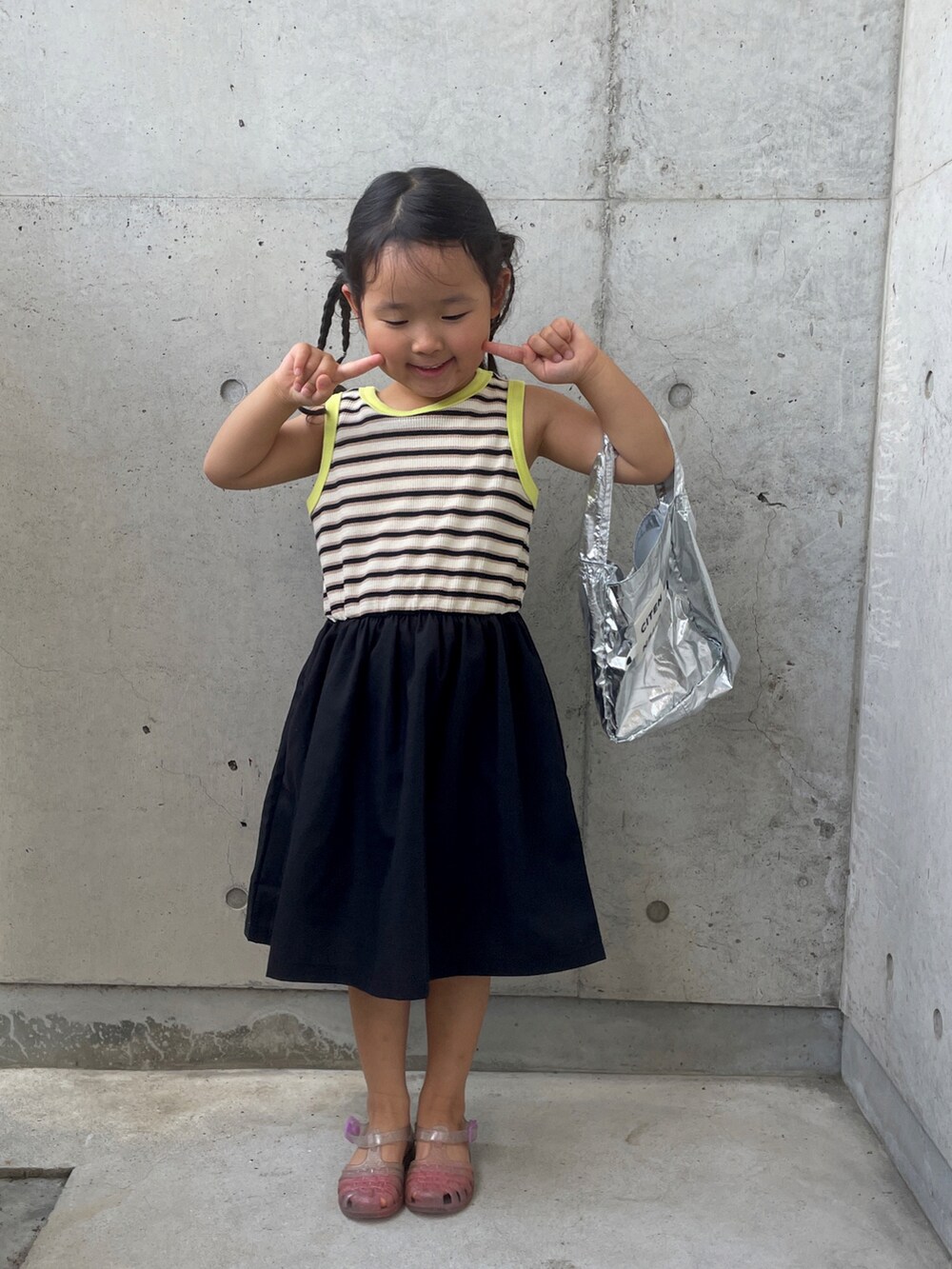 ホワイト系のサンダル、ブラック系のワンピース、シルバー系のハンドバッグを着用したキッズの夏コーディネートの3枚目の写真