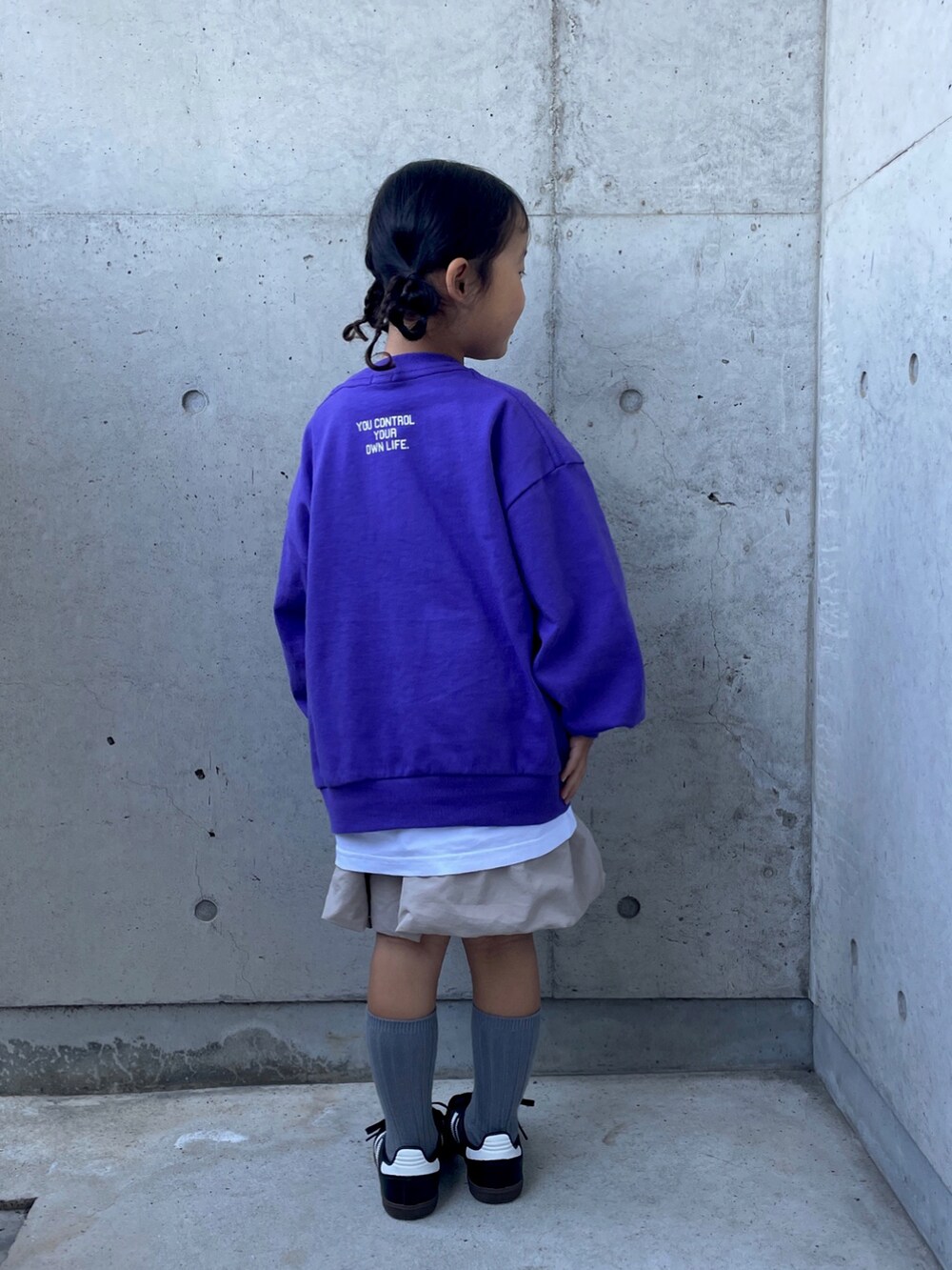 ベージュ系のスカート、パープル系のTシャツ/カットソー、ブラック系のスニーカーを着用したキッズの秋コーディネートの5枚目の写真