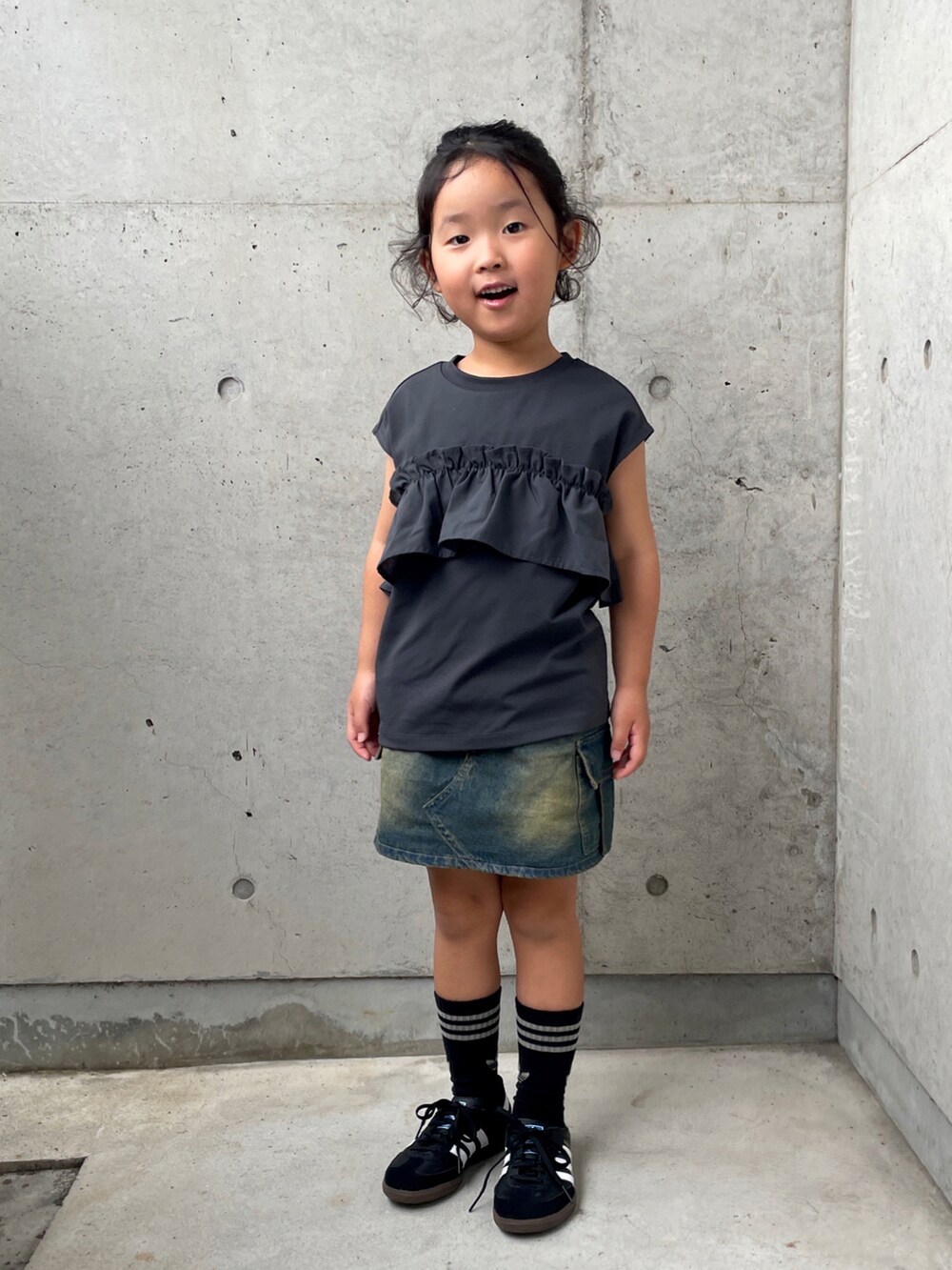 グレー系のタンクトップ、ブルー系のスカート、ブラック系のスニーカーを着用したキッズの夏コーディネートの5枚目の写真