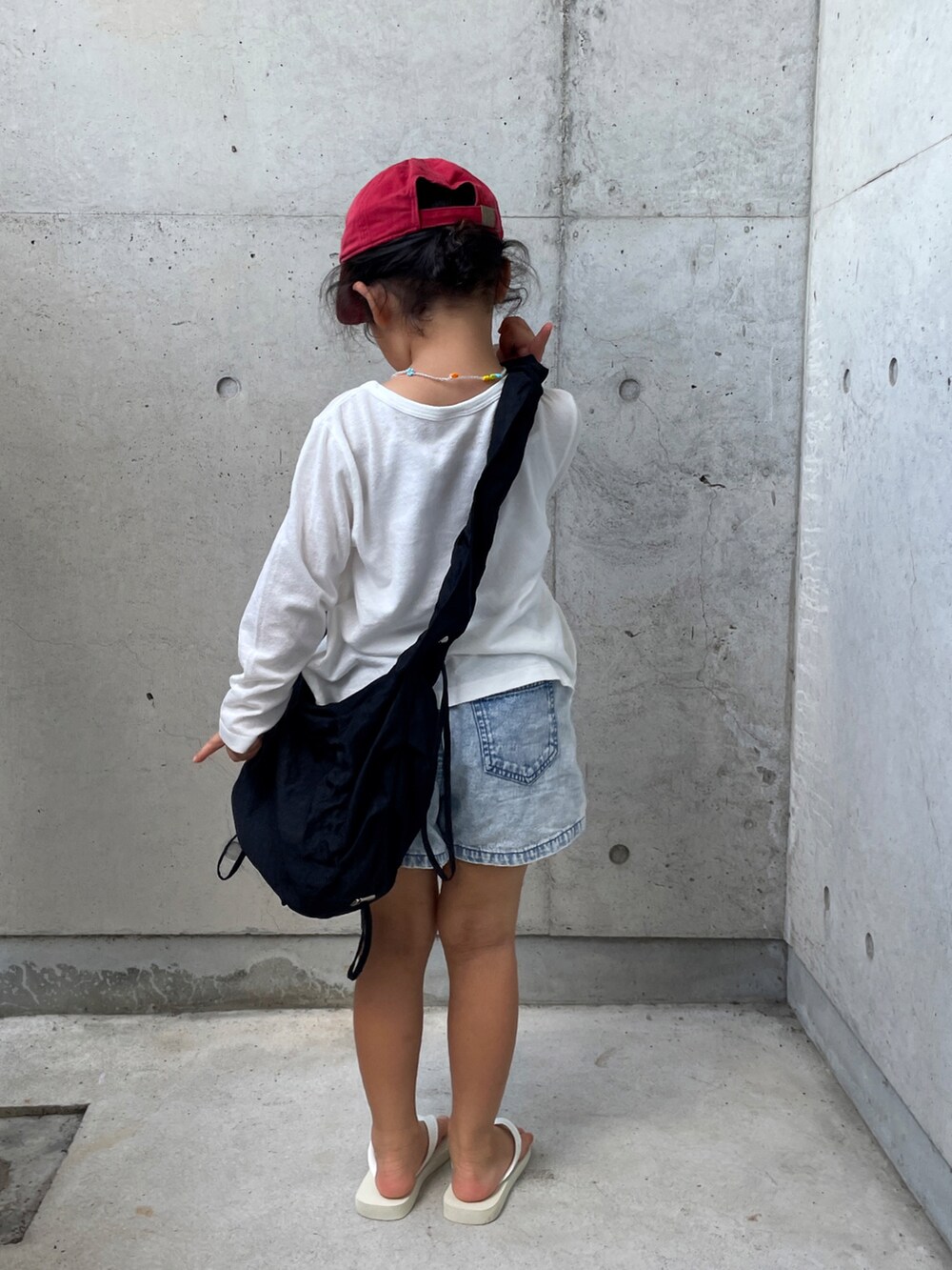 ブラック系のショルダーバッグ、ブルー系のデニムパンツ、ホワイト系のサンダルを着用したキッズの夏コーディネートの5枚目の写真