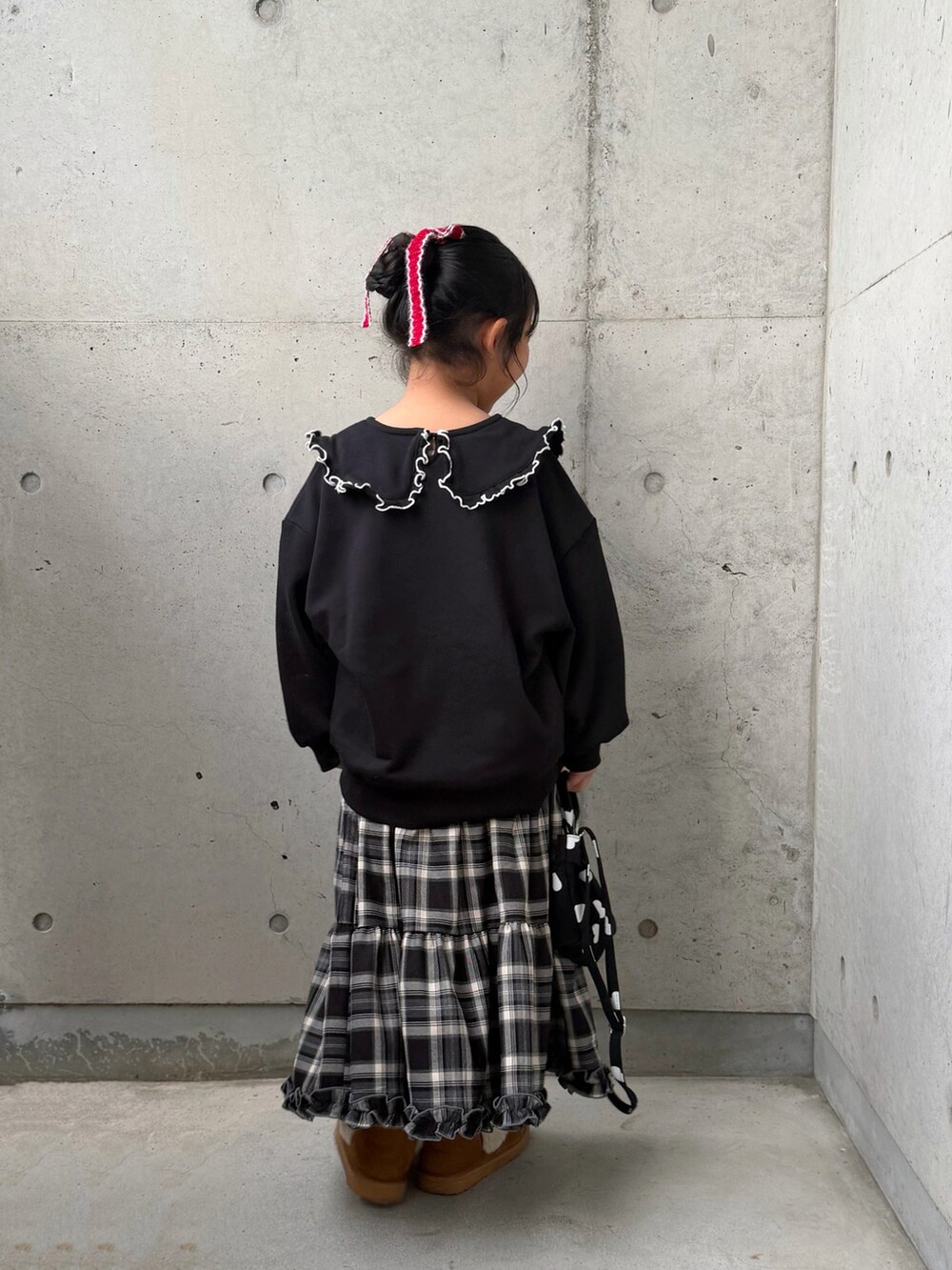 ブラック系のスウェット、ブラウン系のスカート、ブラック系のショルダーバッグを着用したキッズの秋コーディネートの3枚目の写真