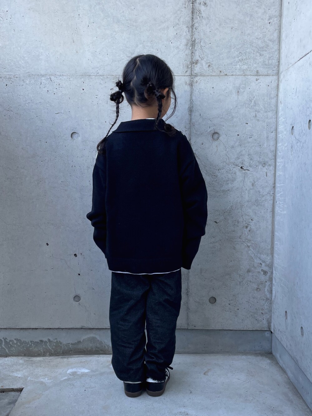 ブラック系のパンツ、ブラック系のニット/セーター、ホワイト系のTシャツ/カットソーを着用したキッズの秋コーディネートの2枚目の写真