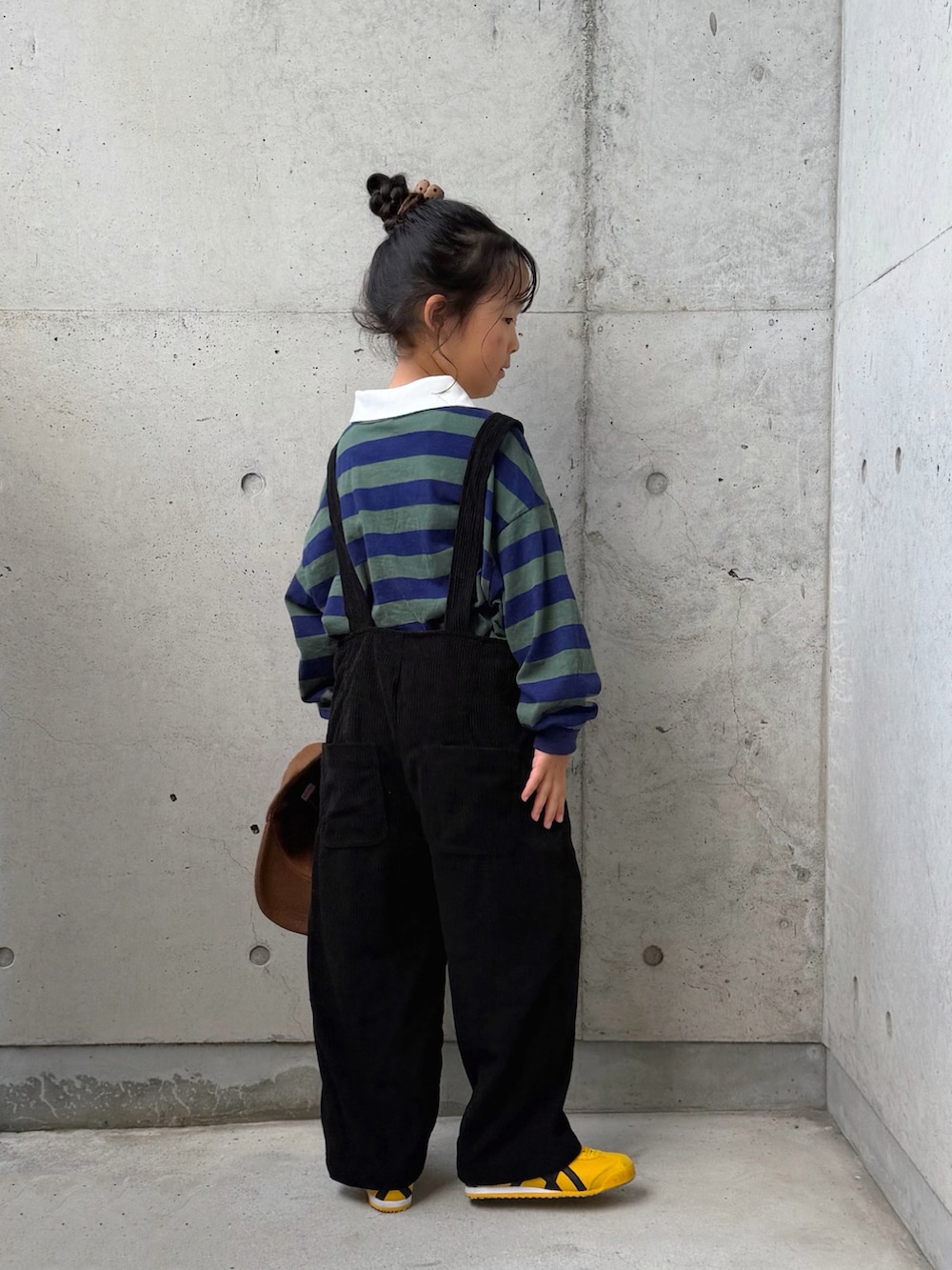 グリーン系のポロシャツ、イエロー系のスニーカー、ブラック系のサロペット/オーバーオールを着用したキッズの秋コーディネートの3枚目の写真