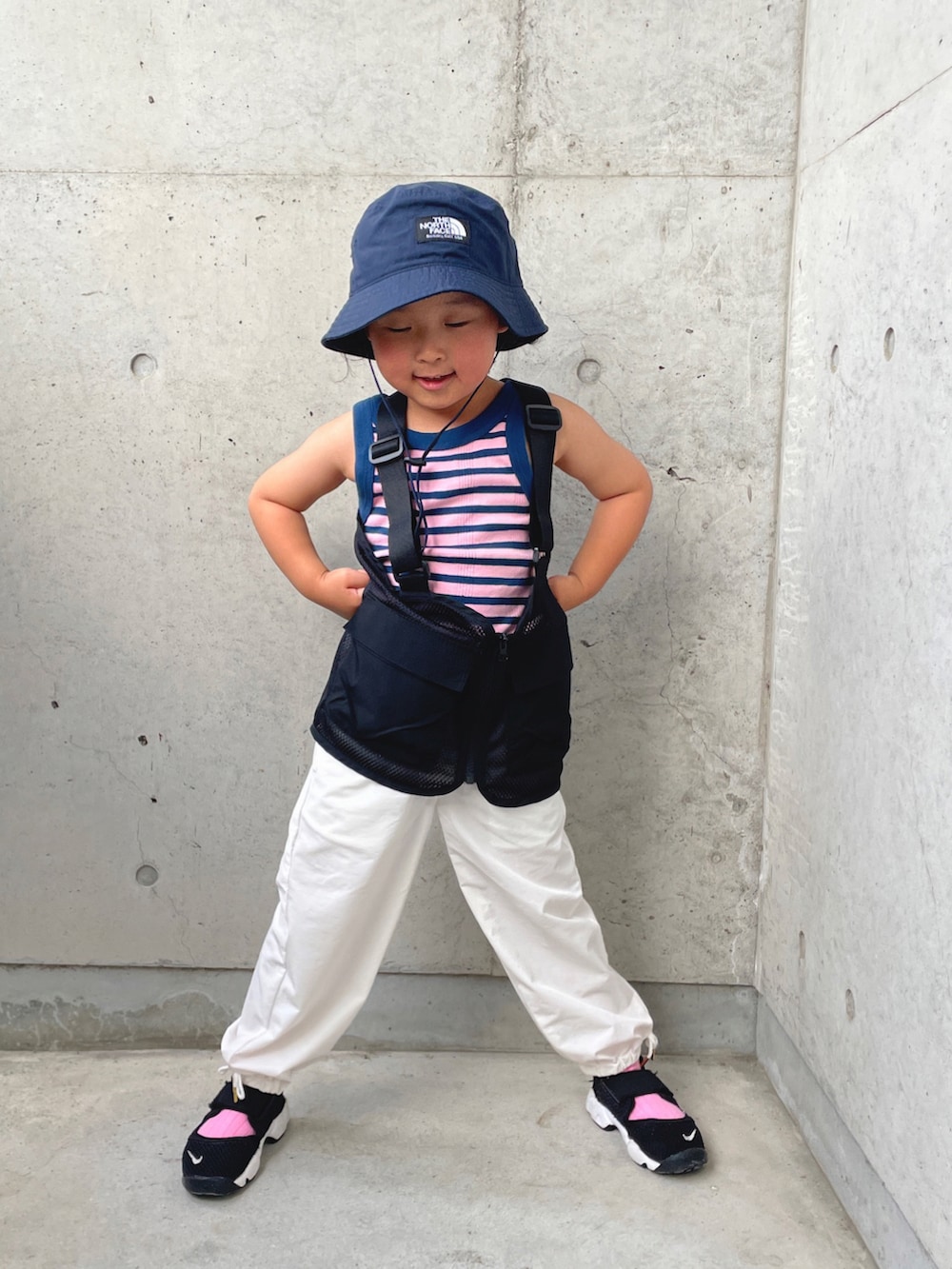 ブルー系のタンクトップ、ブラック系のベスト、ホワイト系のカーゴパンツを着用したキッズの春コーディネートの3枚目の写真