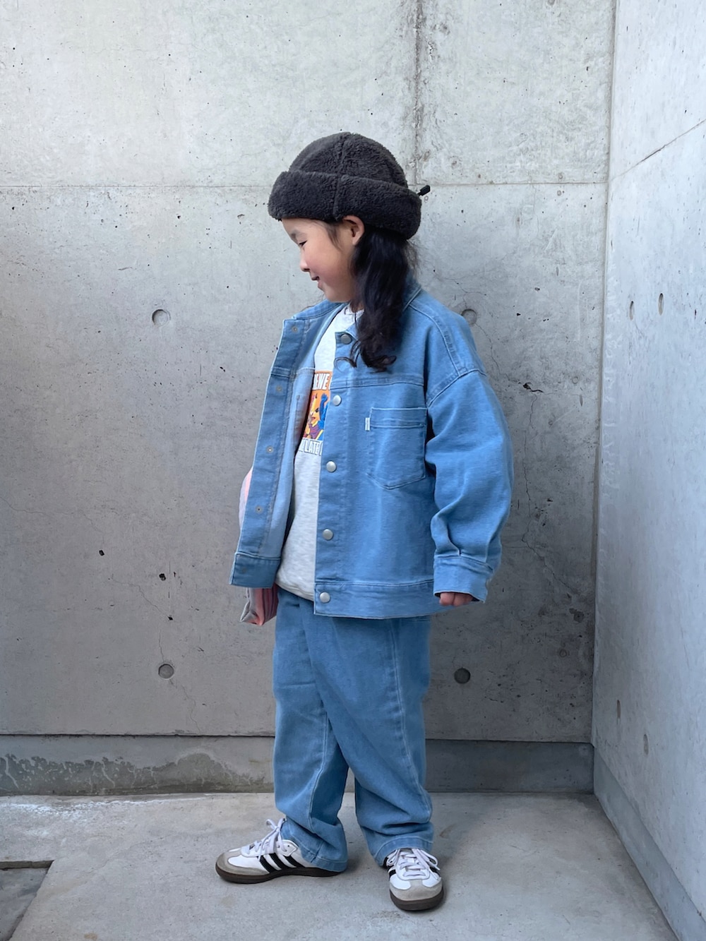 ブルー系のデニムジャケット、オレンジ系のトートバッグ、グレー系のスウェットを着用したキッズの冬コーディネートの2枚目の写真
