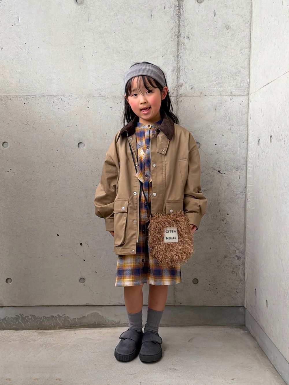 ベージュ系のミリタリージャケット、イエロー系のワンピース、グレー系のその他シューズを着用したキッズの冬コーディネートの4枚目の写真