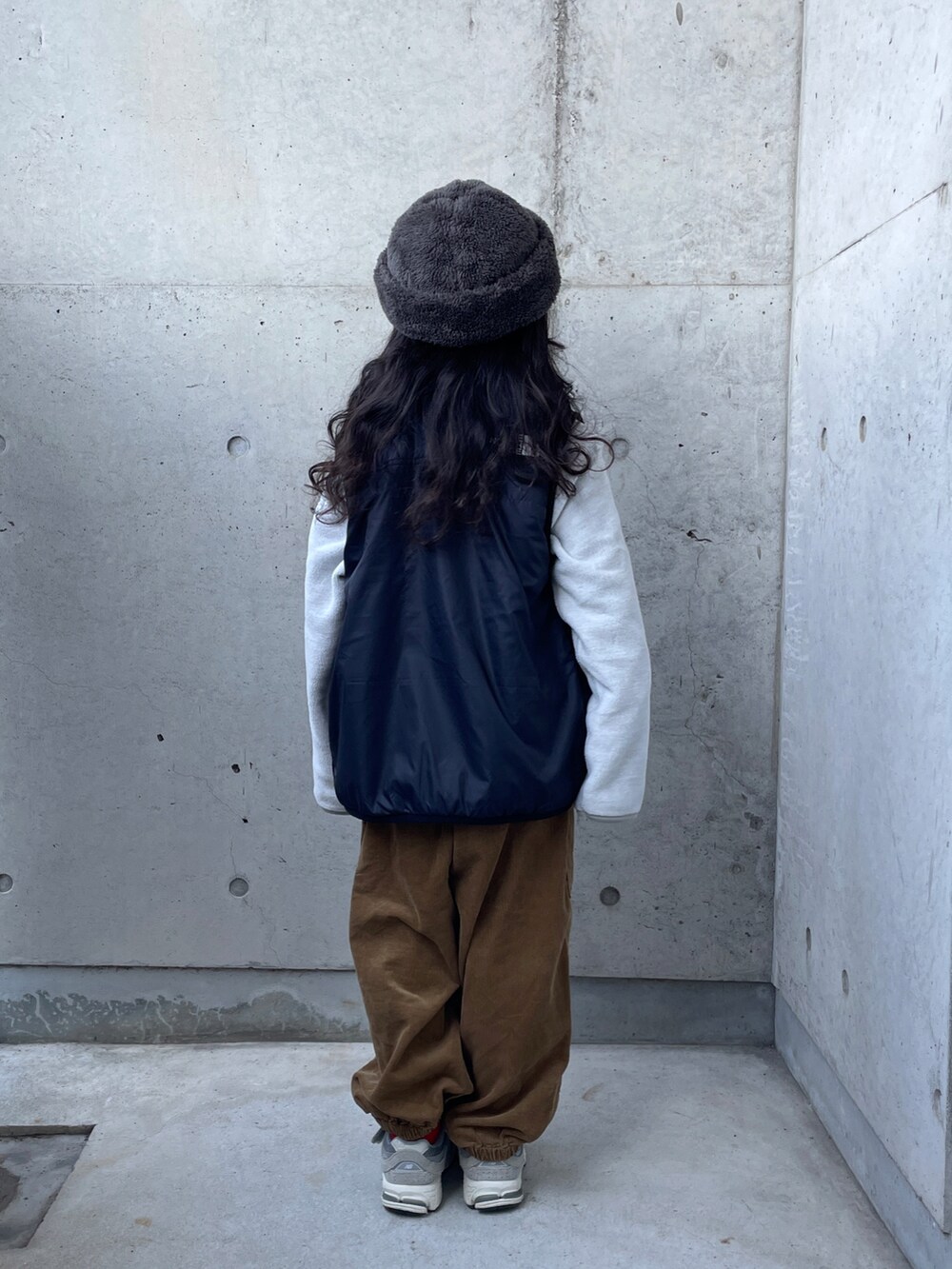 グレー系のトップス、ブラック系のベスト、イエロー系のその他パンツを着用したキッズの冬コーディネートの3枚目の写真