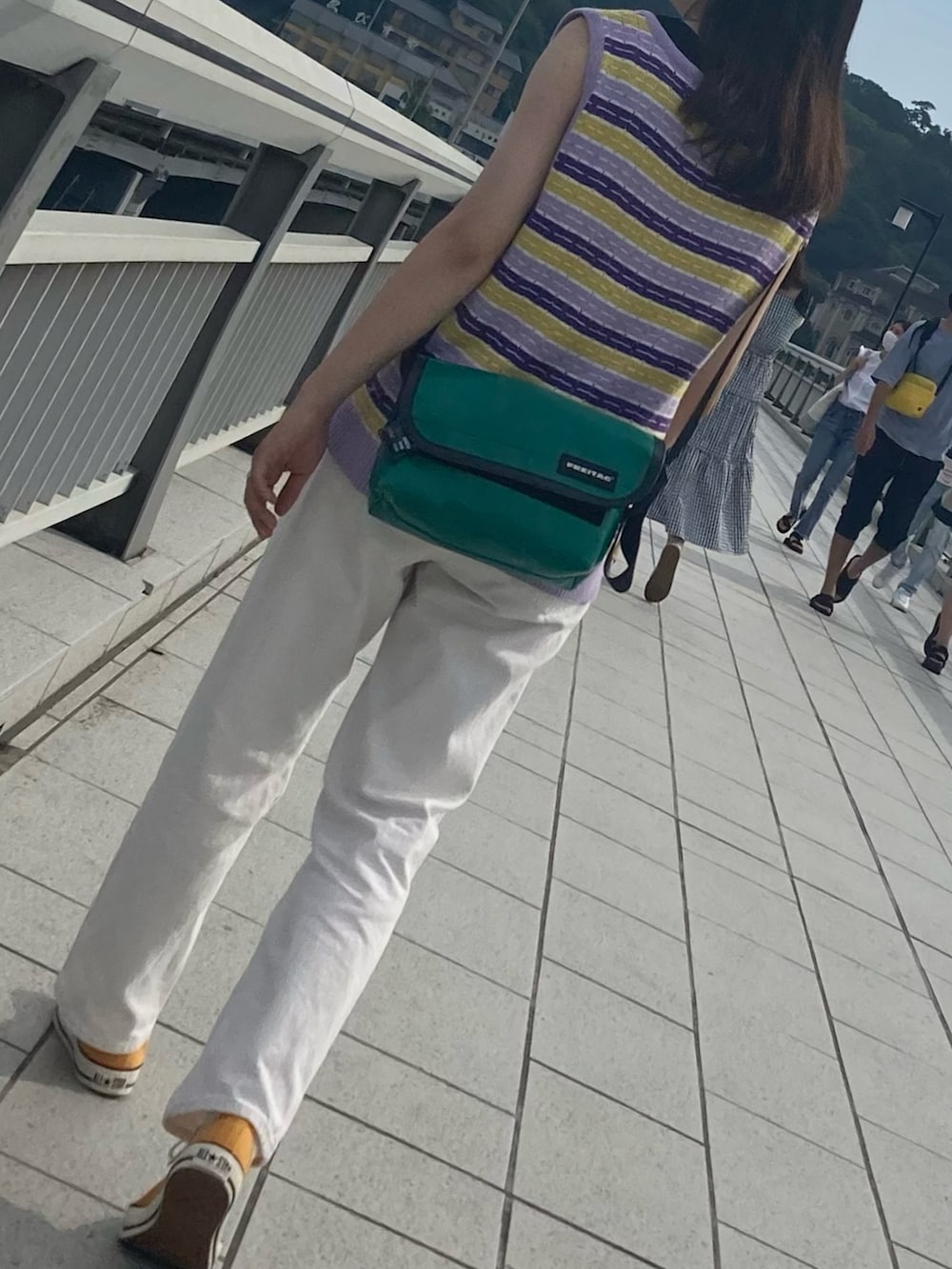 ホワイト系のデニムパンツ、パープル系のベスト、オレンジ系のスニーカーを着用したレディースの夏コーディネートの2枚目の写真