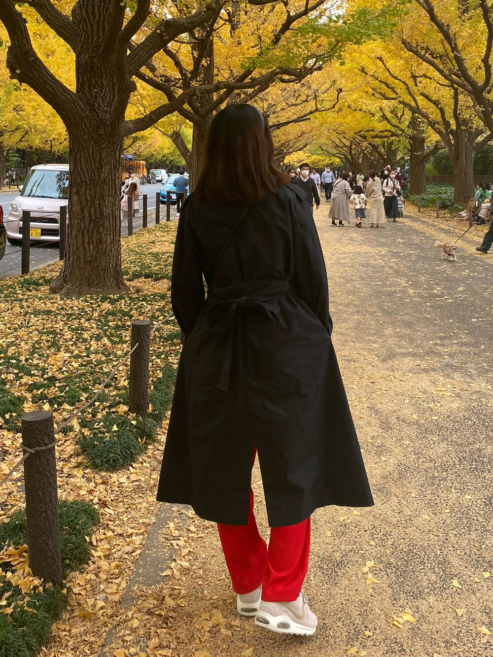 ブラック系のトレンチコート、ブラック系のTシャツ/カットソー、ベージュ系のスニーカーを着用したレディースの秋コーディネートの2枚目の写真