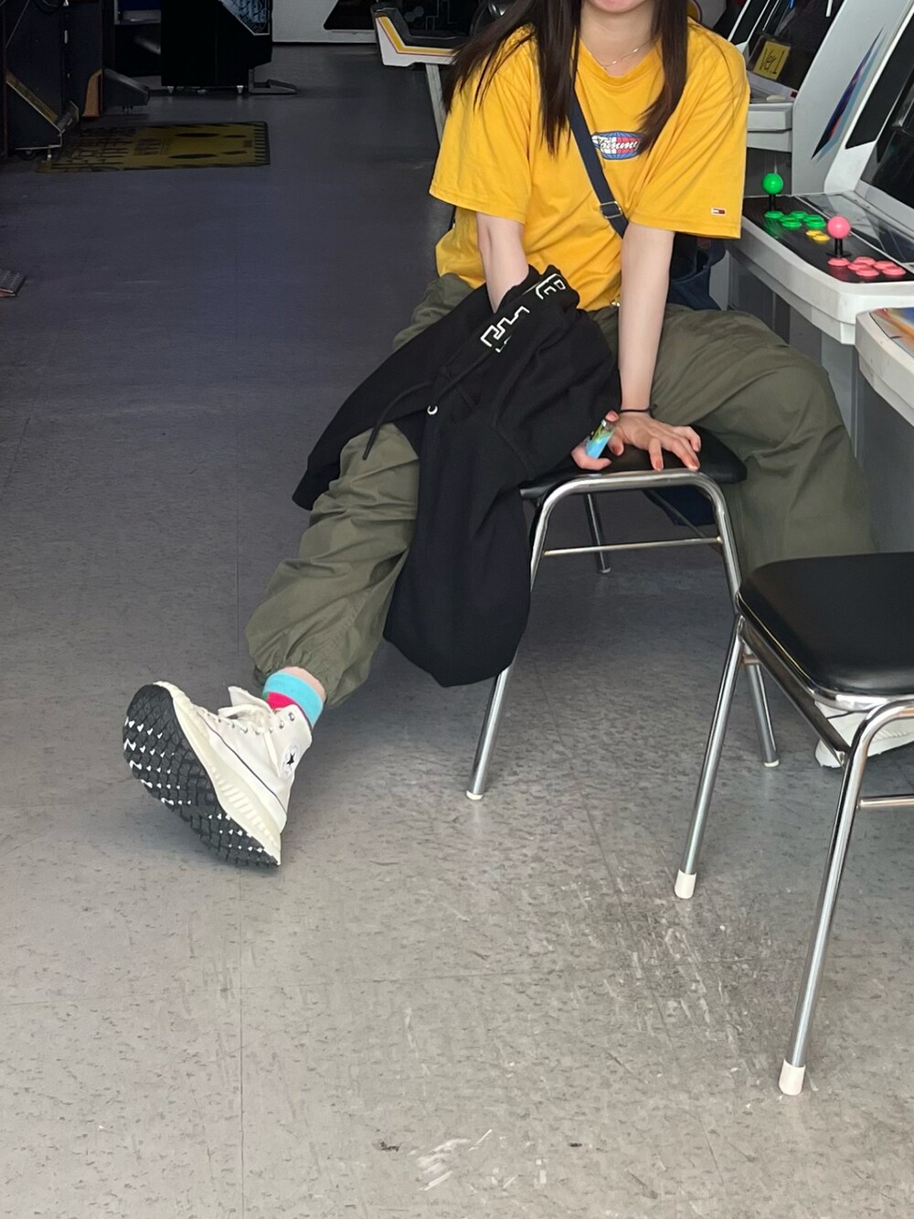 イエロー系のTシャツ/カットソー、グリーン系のカーゴパンツ、ブラック系のパーカーを着用したレディースの春コーディネートの2枚目の写真