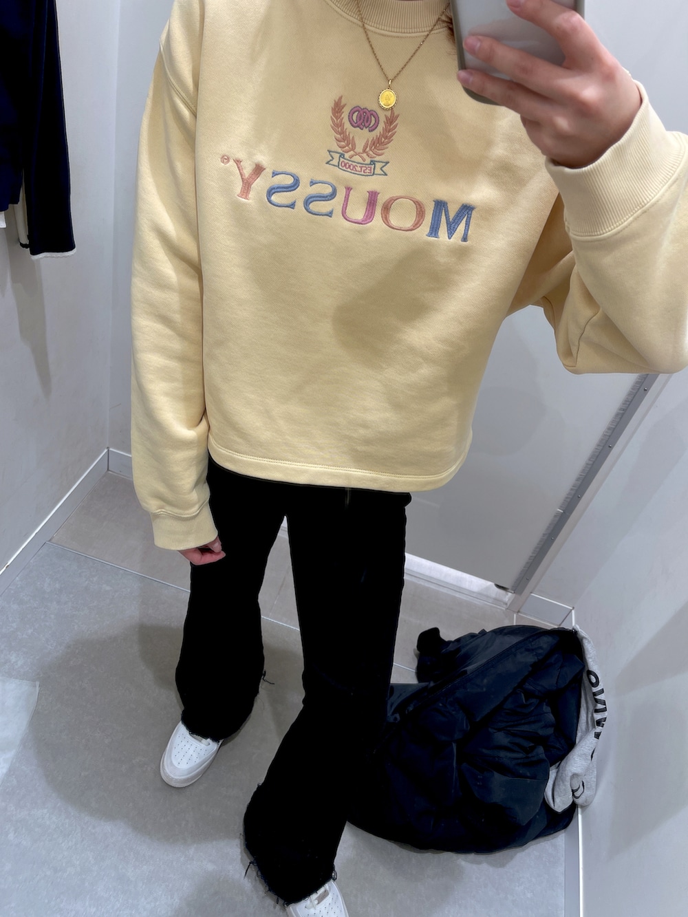 ブラック系のデニムパンツ、ホワイト系のスニーカー、ブラック系のダウンジャケット/コートを着用したレディースの冬コーディネートの2枚目の写真