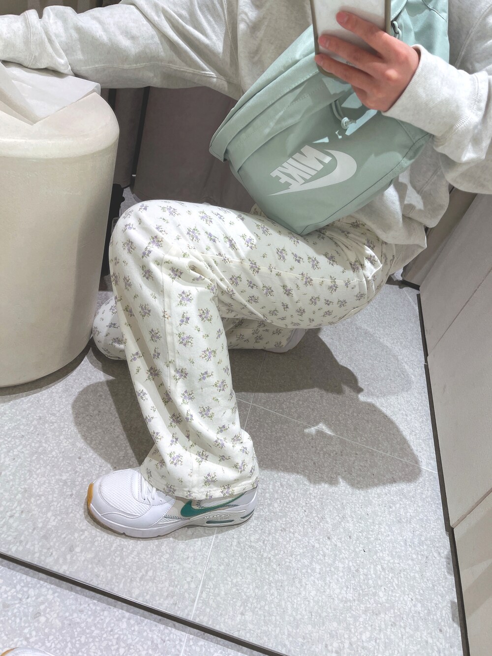 ホワイト系のデニムパンツ、ホワイト系のスニーカー、グリーン系のボディバッグ/ウエストポーチを着用したレディースの冬コーディネートの2枚目の写真