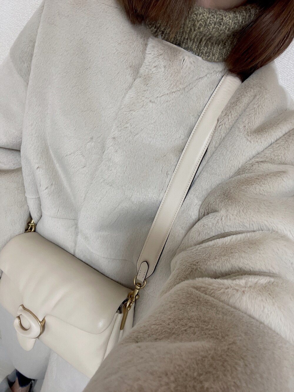 ホワイト系のハンドバッグ、ホワイト系のその他アウター、ブルー系のデニムパンツを着用したレディースの冬コーディネートの2枚目の写真