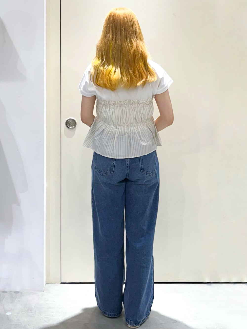 ブルー系のデニムパンツ、シルバー系のトートバッグ、ベージュ系のTシャツ/カットソーを着用したレディースの春コーディネートの7枚目の写真