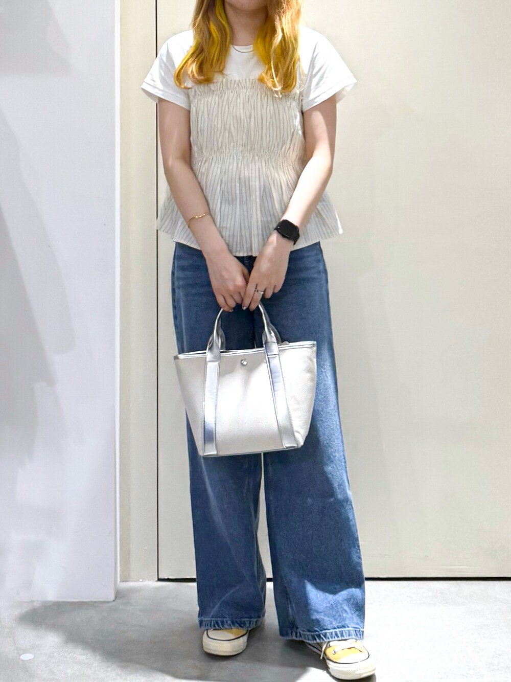 ブルー系のデニムパンツ、シルバー系のトートバッグ、ベージュ系のTシャツ/カットソーを着用したレディースの春コーディネートの5枚目の写真